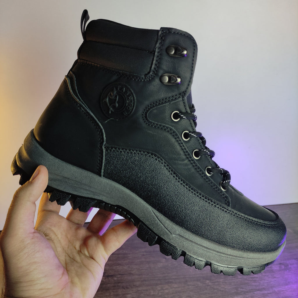 Black hiking boot held by a hand with a blurred background