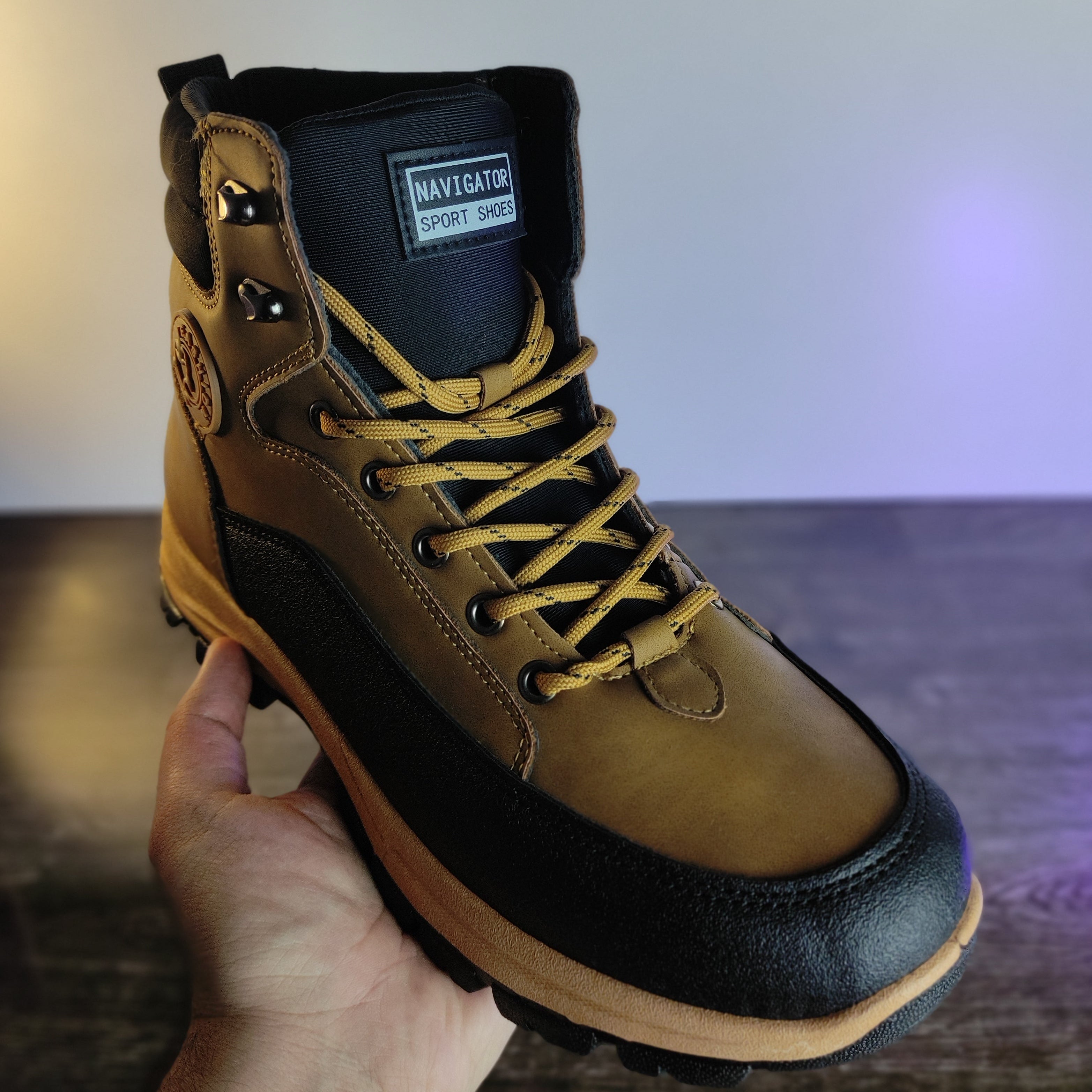 Brown leather boot with black sole held by a hand against a blurred background